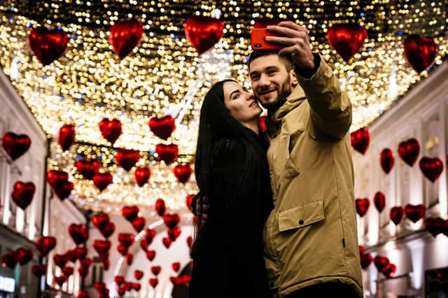 A couple poses for a selfie under heart-shaped balloons displayed for Valentine's Day in downtown Moscow on February 13, 2020. (Photo by Dimitar DILKOFF / AFP) (Photo by DIMITAR DILKOFF/AFP via Getty Images)