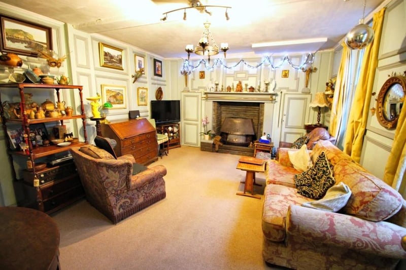 A large reception room with feature fireplace and wall panelling.