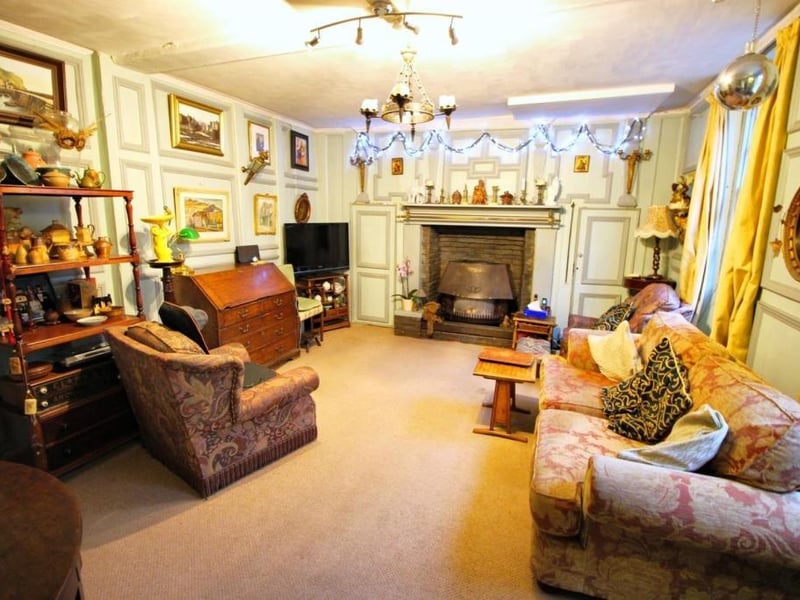 A large reception room with feature fireplace and wall panelling.