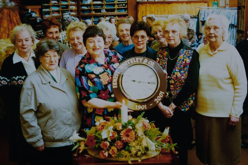 Here is Ann Clough (central left), next to Sue Walker (central right) holding the shop's special centenary clock in 2001.