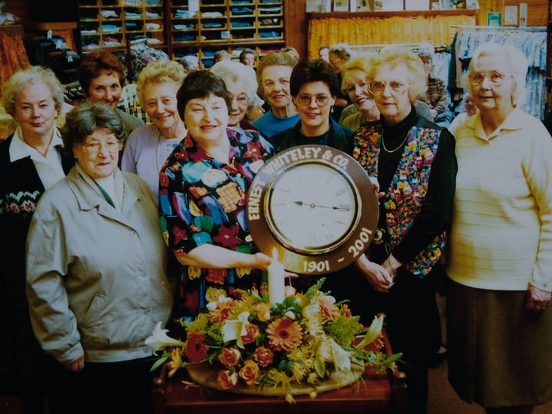 Here is Ann Clough (central left), next to Sue Walker (central right) holding the shop's special centenary clock in 2001.
