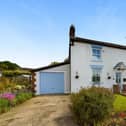 The front aspect of the cottage with its lawned garden and flower borders.