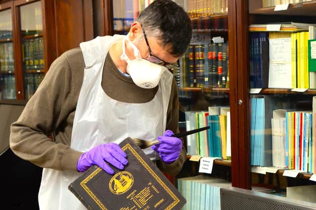 Library curator undertaking essential book restoration work.