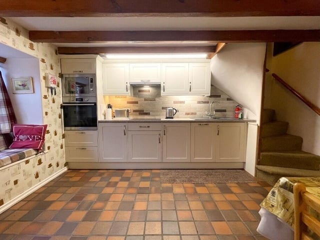 A spacious beamed dining kitchen with window seat feature, and a winding staircase to the first floor.