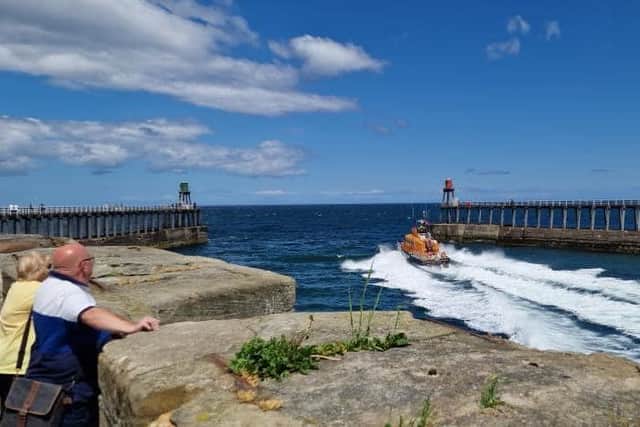 Onlookers watch as the all weather lifeboat leaves Whitby Harbour. Image credit: Whitby RNLI/Julian Goodwill