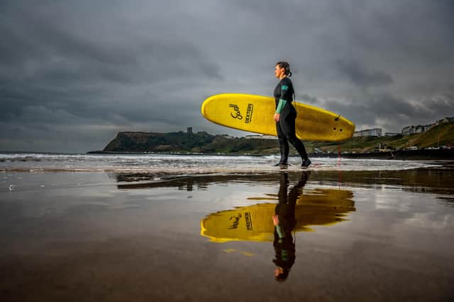Scarborough Castle towers over the bay as a surfer heads to the waters in North Bay