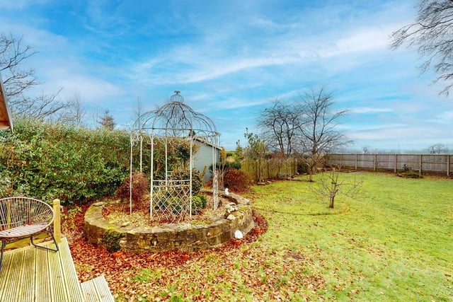 The lawned rear garden has established trees with a summer house and pergola.