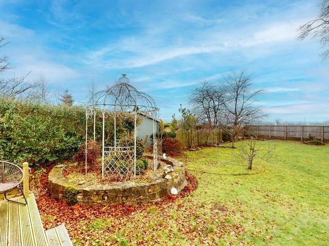 The lawned rear garden has established trees with a summer house and pergola.