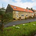 A front view of the traditional stone cottage in its lovely village setting.