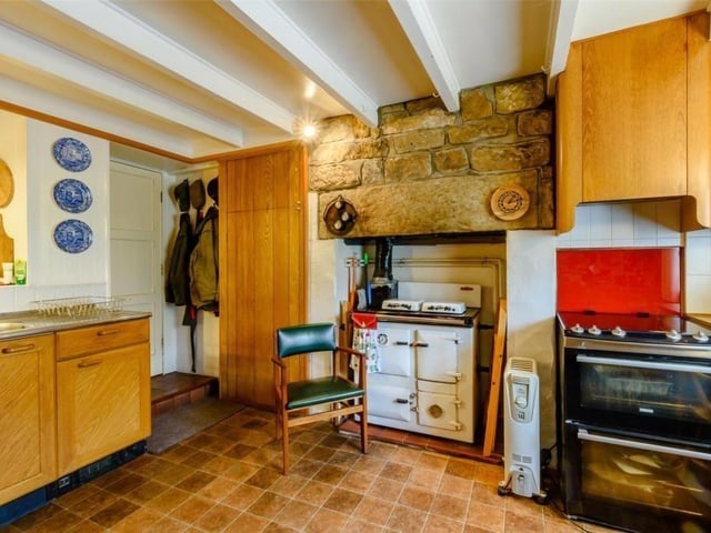 A beamed farmhouse style kitchen has fitted units.