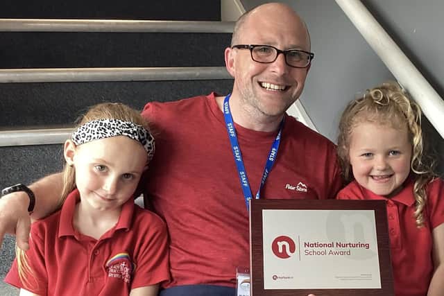 Headteacher Matthew Davis shows off the award with the help of pupils