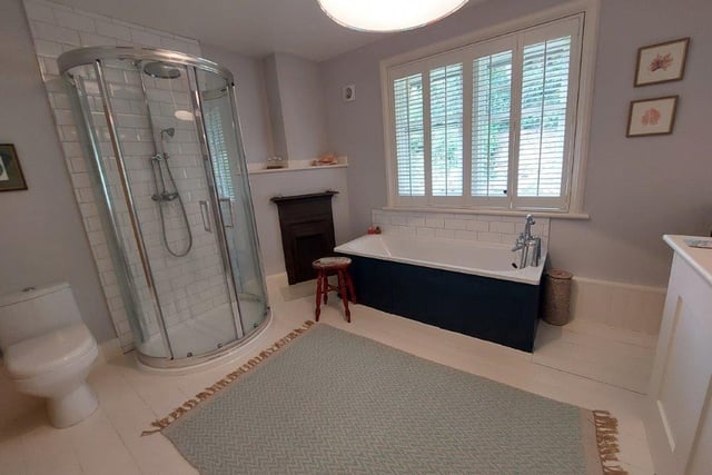 The bathroom has both bath and shower cubicle, with a fireplace, and a large window.