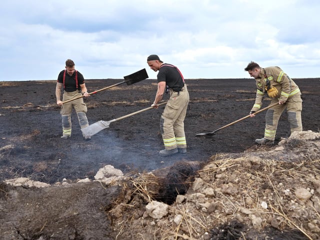Firefighters work on the smouldering land