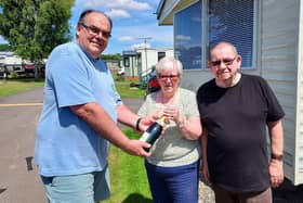 Mark Goodson, owner of Wayside Holiday Park, presents Geoff and Elaine Dent with a bottle of champagne.