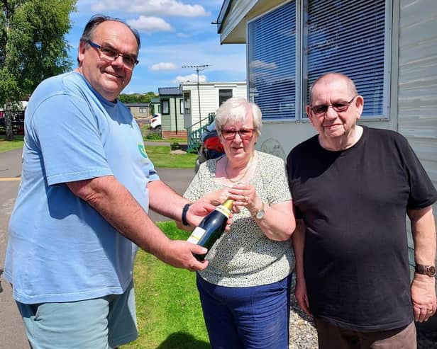 Mark Goodson, owner of Wayside Holiday Park, presents Geoff and Elaine Dent with a bottle of champagne.