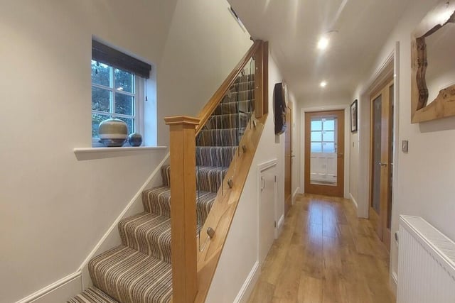 A carpeted staircase with glass balustrade leads to the first floor from the hallway.