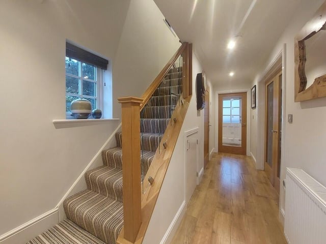 A carpeted staircase with glass balustrade leads to the first floor from the hallway.