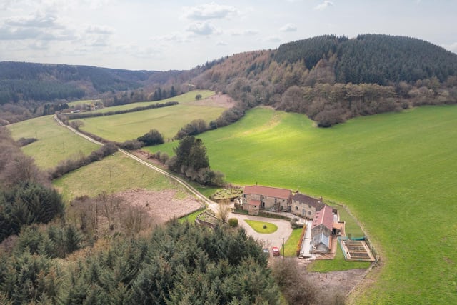 An aerial view of the farmhouse and its surroundings in an area of natural beauty.