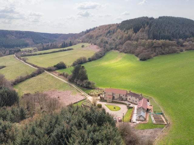 An aerial view of the farmhouse and its surroundings in an area of natural beauty.