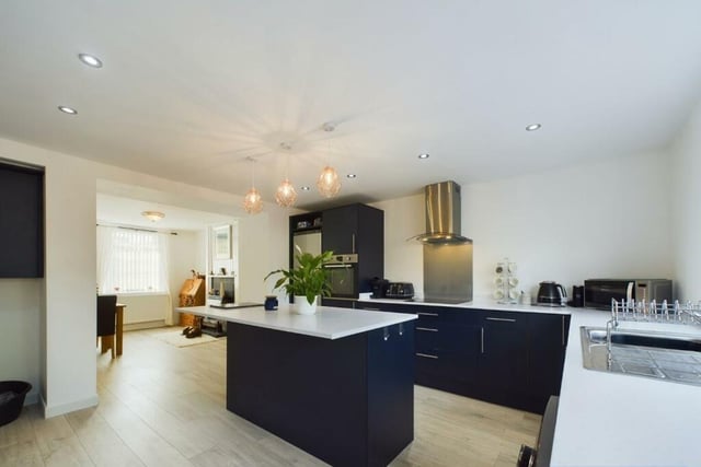 A modern, open plan kitchen with a central island, fitted units and integrated appliances.