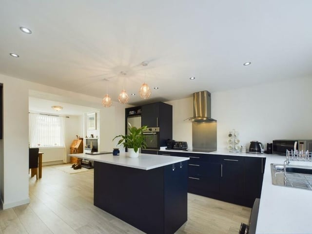 A modern, open plan kitchen with a central island, fitted units and integrated appliances.