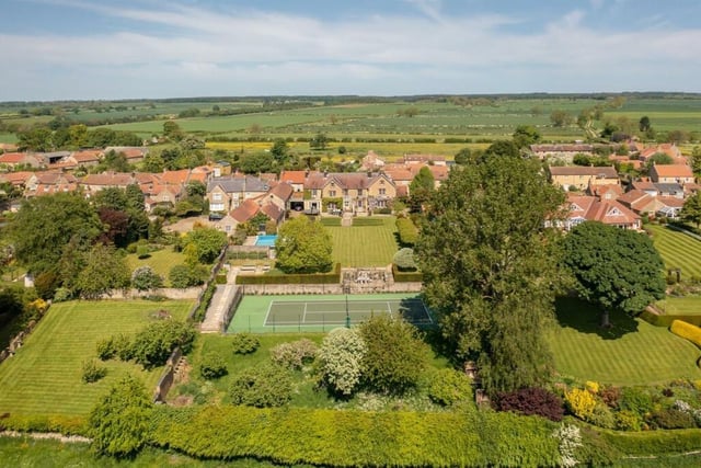 A view towards and over the property in its glorious setting, with the sunken all-weather tennis court in the foreground.