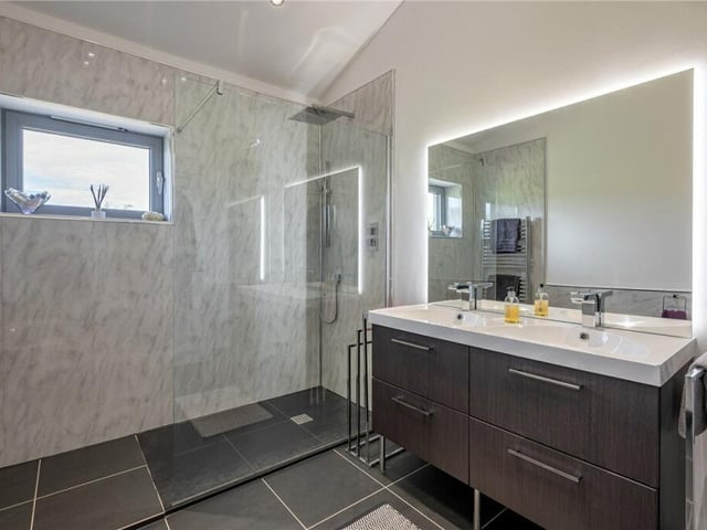 A stylish shower room, with twin washbasins and vanity units.