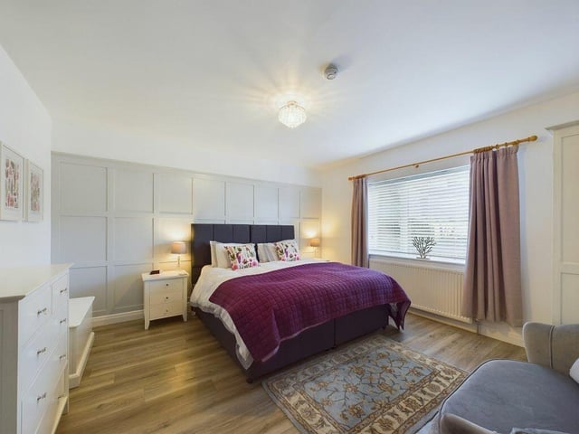 The ground floor double bedroom has a panelled wall and fitted furniture.