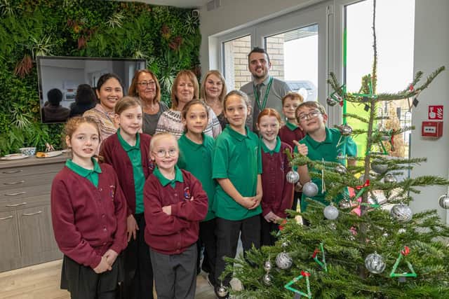 Left to right: Laarni Leggatt, Music Teacher at Overdale Community Primary School; Jill Woodhead, Sales Executive at Lovell Later Living; Paula Broadbent, Managing Director at Lovell Later Living; Debra Keller, Customer Experience Manager at Lovell Later Living; Robert Bowman, Head Teacher at Overdale Community Primary School with pupils from Overdale Community Primary School by the Christmas tree they decorated