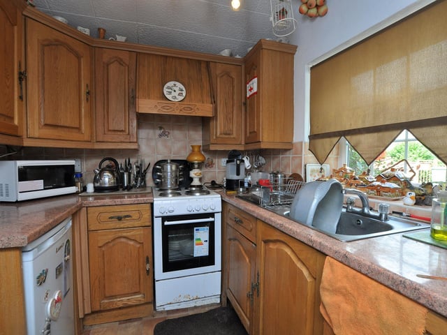 Fitted units line the kitchen walls, with a large window allowing plenty of natural light.