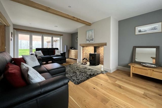 A large, inglenook fireplace with a log burner is a central feature in the living room, that has bi-fold doors to outside.