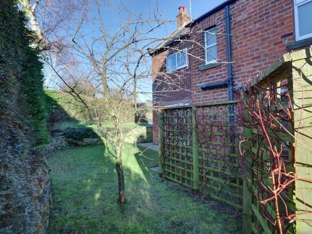 Lawned gardens are to one side of the property, while the other has a patio and vegetable garden, with outbuildings.