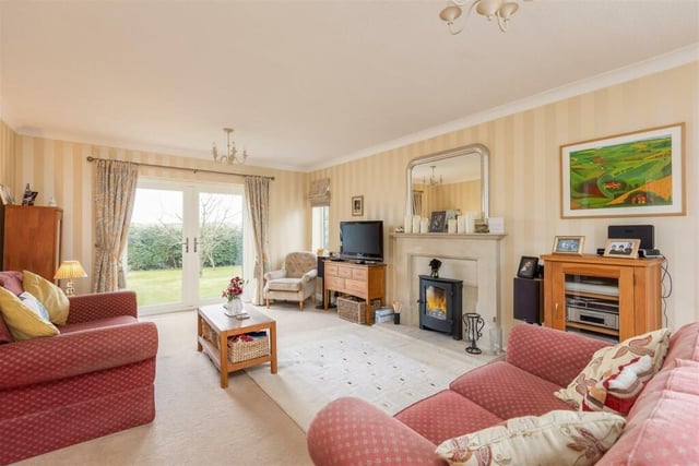 A bright sitting room with central fireplace and patio doors out to the gardens.