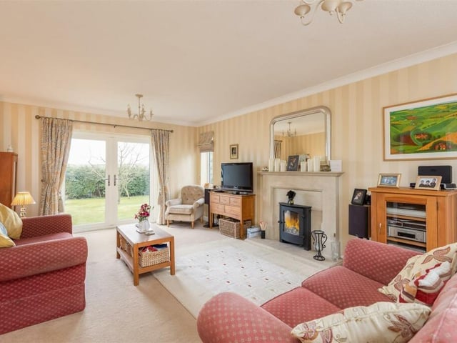 A bright sitting room with central fireplace and patio doors out to the gardens.