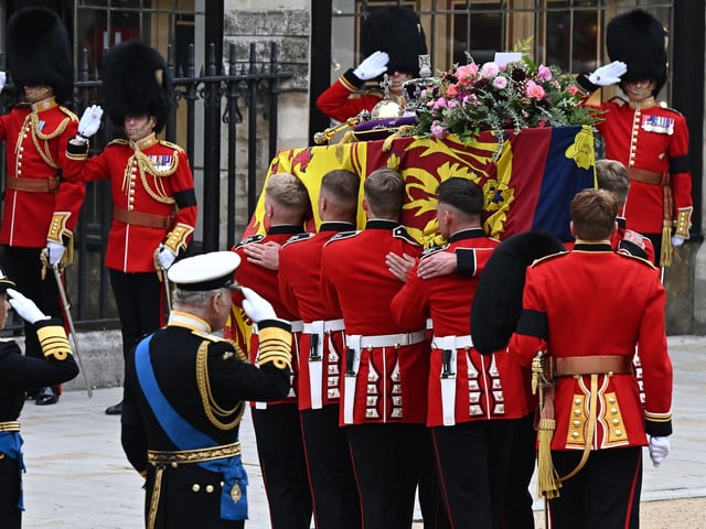 King Charles III (C) salutes as a Bearer Party of The Queen's Company, 1st Battalion Grenadier Guards carries the coffin of Queen Elizabeth II, draped in the Royal Standard and adorned with the Imperial State Crown and the Sovereign's orb and sceptre to Westminster Abbey. (Photo by Oli SCARFF / AFP) (Photo by OLI SCARFF/AFP via Getty Images)