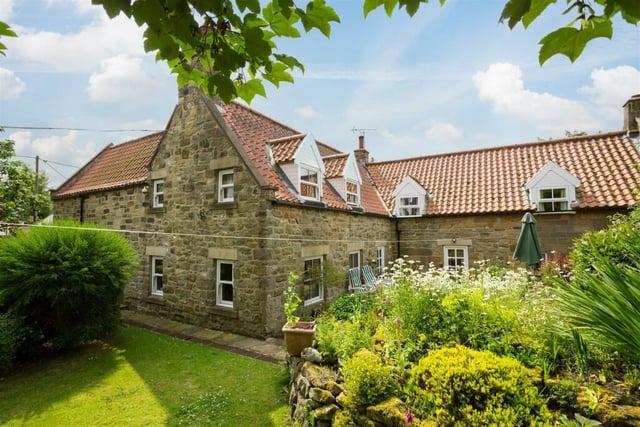 A rear view of the extended stone-built cottage with lovely gardens.