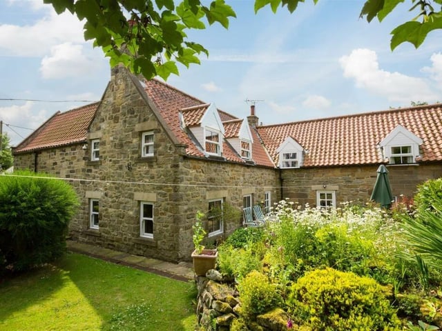 A rear view of the extended stone-built cottage with lovely gardens.