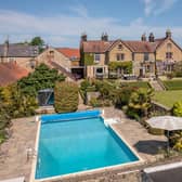 An overview of the impressive Manor House with swimming pool and tropical garden in the foreground.