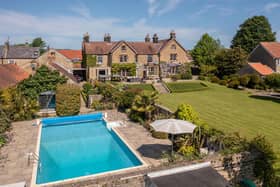 An overview of the impressive Manor House with swimming pool and tropical garden in the foreground.