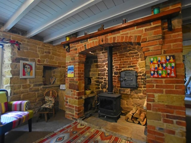 A closer look at the lovely old fireplace, flanked by exposed stone walls and a beamed ceiling.