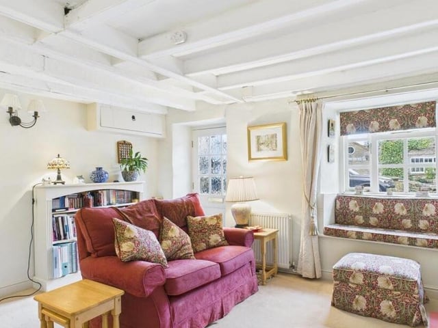 A section of the beamed living room that has a charming window seat.
