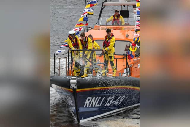 Volunteer crew member Max Burnett pops the cork.photo: RNLI/Ceri Oakes