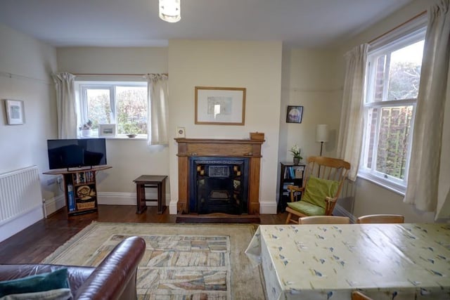 This sitting room, with stripped and varnished wooden floor, has a fireplace with oak surround, and a sash window.