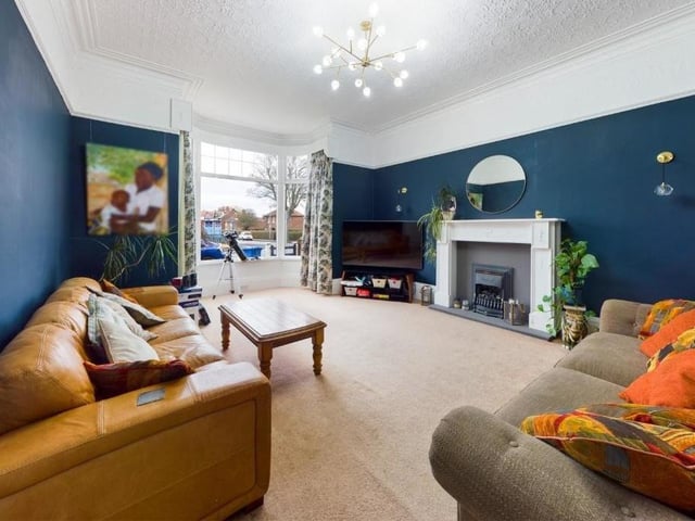 The spacious lounge with a bay window and feature fireplace.