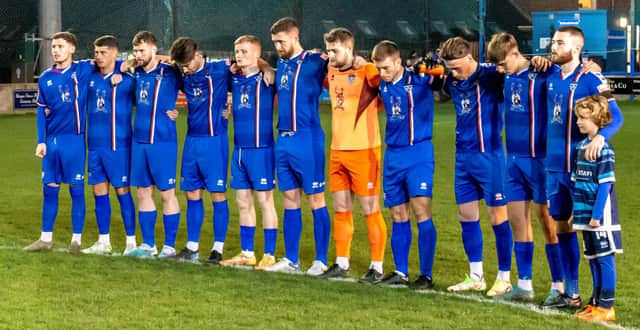The Whitby Town players observe a minute's silence in tribute to former manager Tony Lee. PHOTO BY BRIAN MURFIELD