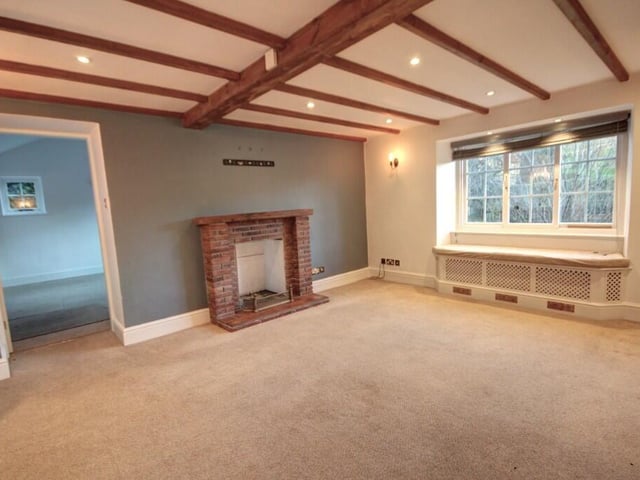 This spacious beamed lounge, with panelling to one wall, has a brick fireplace for a gas fire, and large sash windows, including one with a lovely window seat.
