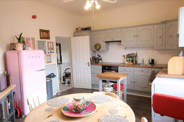 A spacious kitchen with diner has fitted units, an electric oven and hob, and a large sash window.