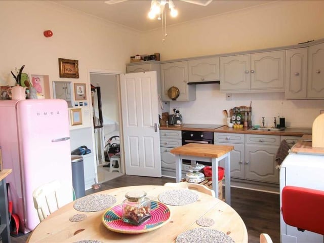 A spacious kitchen with diner has fitted units, an electric oven and hob, and a large sash window.