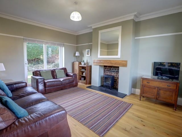 The lounge, with central fireplace and multi-fuel burner, has sliding doors to outside. Decorative details include a cornice and picture rail.
