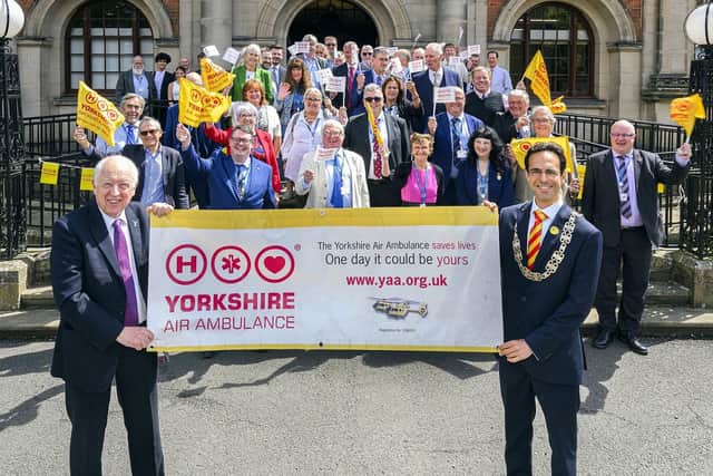 North Yorkshire Council’s elected members are pictured outside County Hall in Northallerton today showing their support after the authority’s chair, Cllr George Jabbour, announced Yorkshire Air Ambulance is his charity of the year. North Yorkshire Council’s leader, Cllr Carl Les, is pictured left in the foreground holding a Yorkshire Air Ambulance banner with Cllr Jabbour.